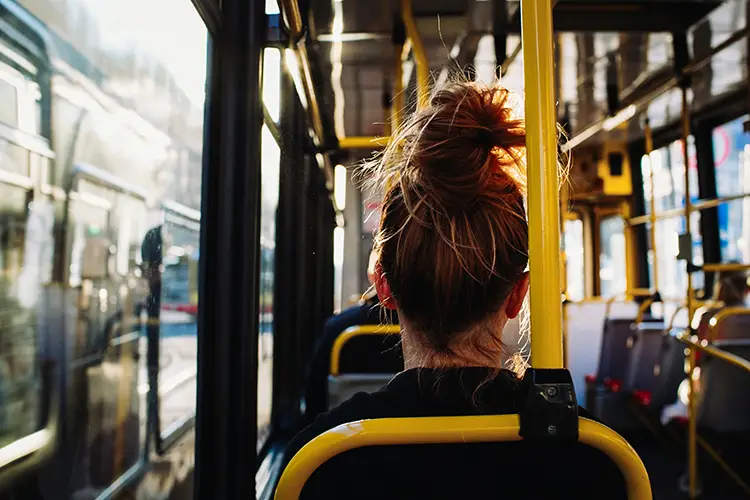 mulher de costas com cabelo preso, sentada dentro de um ônibus. Consultório na Vergueiro com acesso facilitado por ônibus.